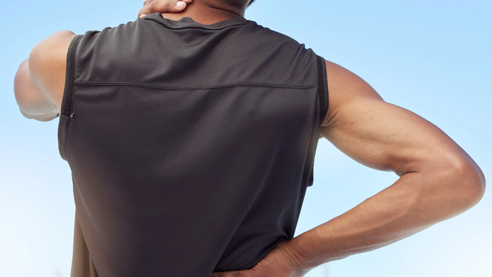 Man stood outside holding neck in pain.