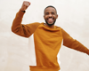 Man in orange sweatshirt cheering with arm in the air.