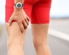 Man in red shorts close up of him holding his upper leg in pain.